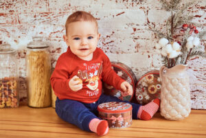 beautiful baby sits table holding nut
